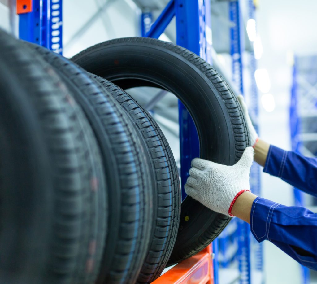 Mechanic picking out a new car tyre from stock - Tyres Soham